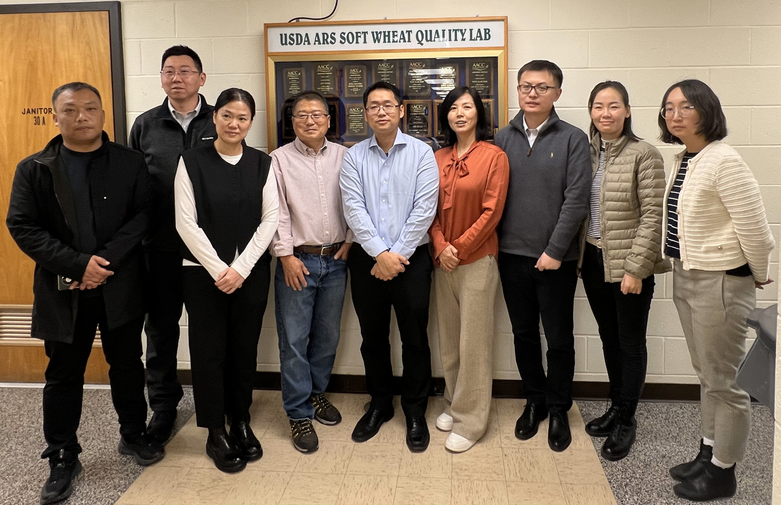Several wheat buyers from China, Dr. Byung Kee Baik, USW staff stand in front of the directory at the ARS Soft Wheat Quality Lab in Wooster, Ohio.