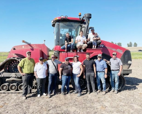Photo shows participants in a USW trade team from the Middle East and North Africa around a large red tractor on the Bill Flory farm in Idaho.