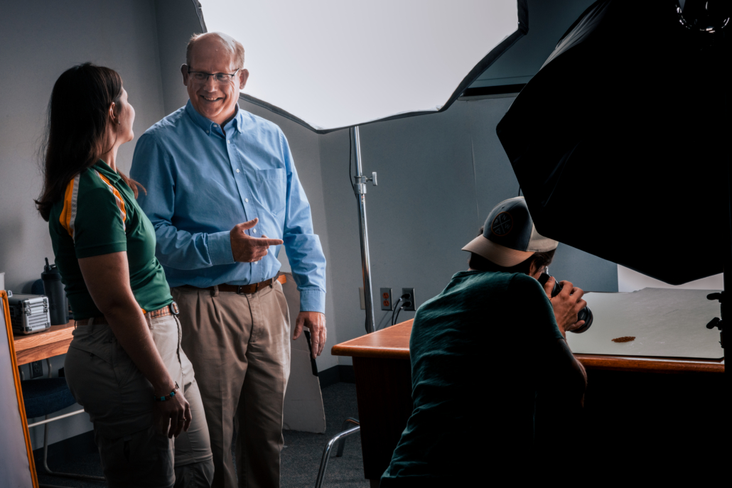 Clair Keene, an Assistant Professor and Agronomist at North Dakota State University, and North Dakota Wheat Commission Policy and Marketing Director Jim Peterson watch as a photographer captures images as part of the kernel photography project.