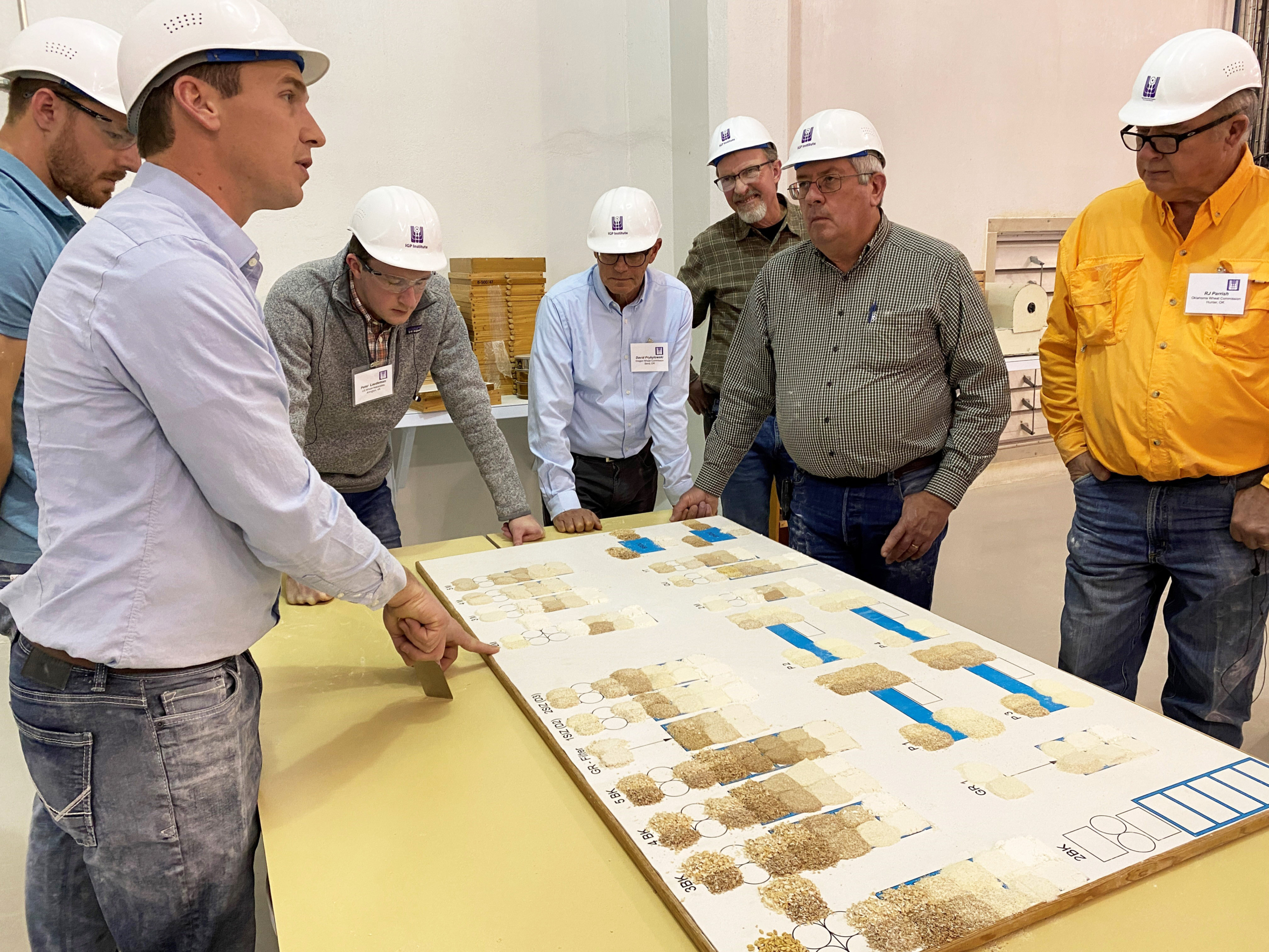 Group of men in a flour mill discussing the milling process at Kansas State University.